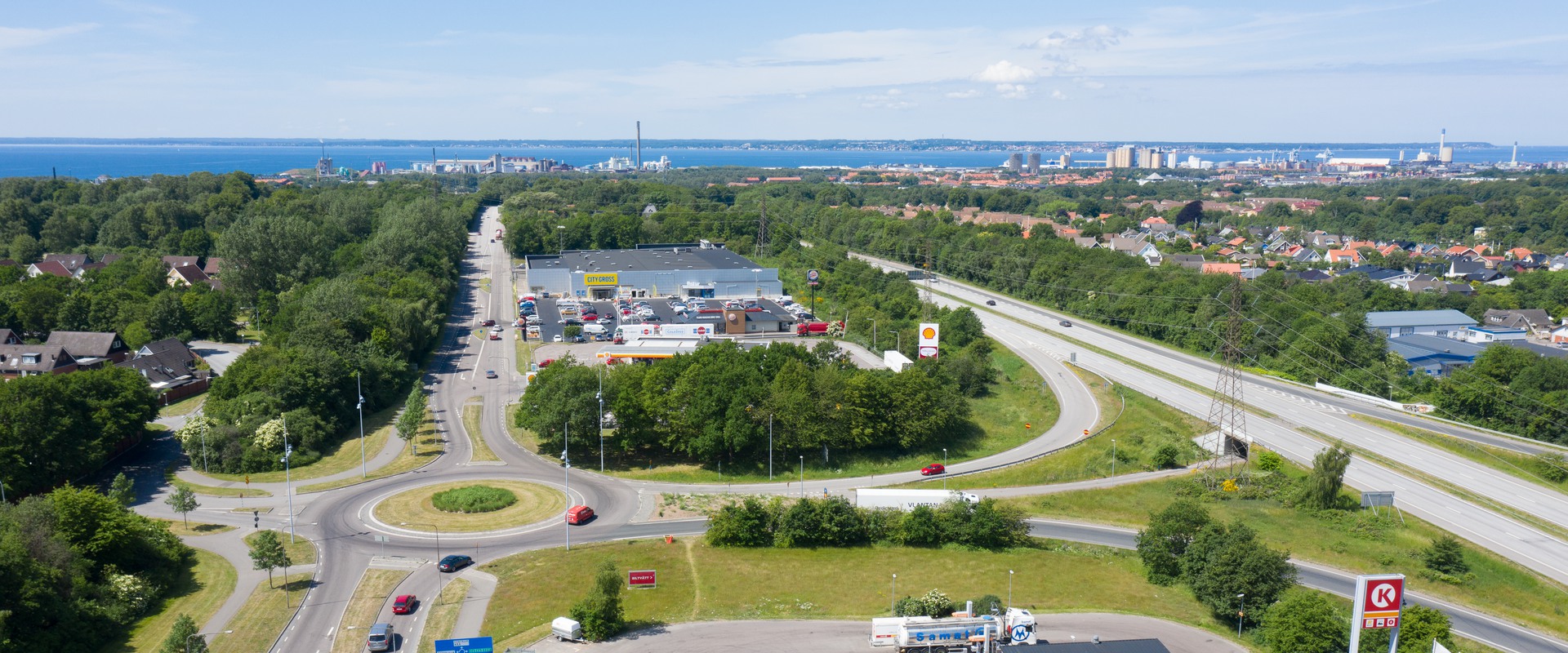 Bilden är tagen från ovan och visar huslängor med grönt runtomkring. Husen är vita med svarta tak