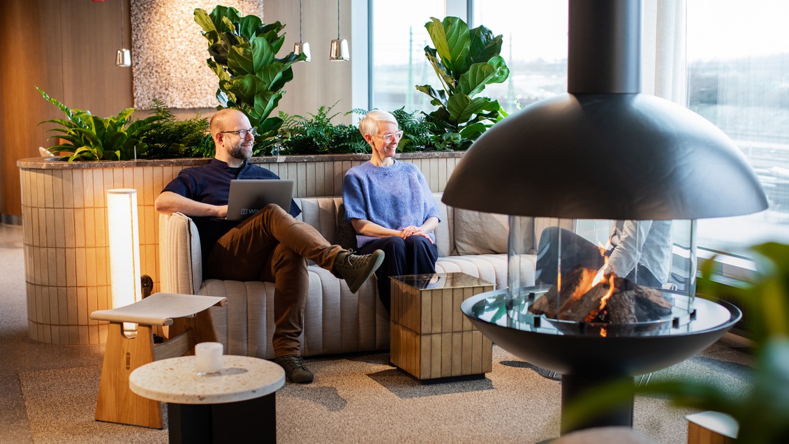 Två personer sitter i en lobby framför en eld